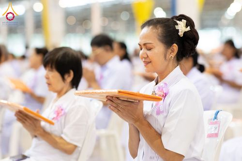 หญิงไทยสวมชุดขาวประนมมือถือผ้าไตรในพิธีทางศาสนา