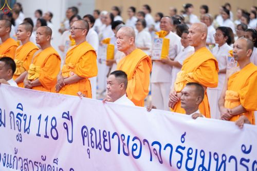 พระภิกษุสงฆ์และพุทธศาสนิกชนยืนถือป้ายไวนิลในงานบุญกฐิน