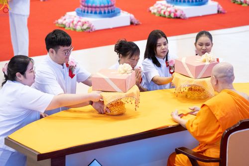 กลุ่มคนในชุดสีขาวกำลังถวายผ้าป่าแด่พระภิกษุสงฆ์ในพิธีทางศาสนา