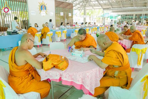 พระภิกษุสงฆ์หลายรูปกำลังนั่งเขียนเอกสารในงานสัมมนาภายในอาคาร