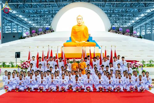 กลุ่มพุทธศาสนิกชนยืนเรียงแถวหน้าพระพุทธรูปองค์ใหญ่ในอาคารสภาธรรมกายสากล