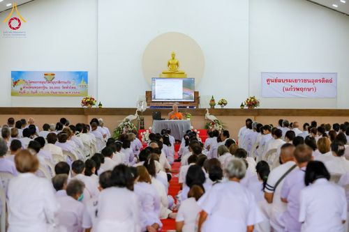 กลุ่มผู้เข้าร่วมโครงการสวมชุดสีขาวนั่งฟังธรรมบรรยายจากพระภิกษุสงฆ์ภายในอาคารปฏิบัติธรรม