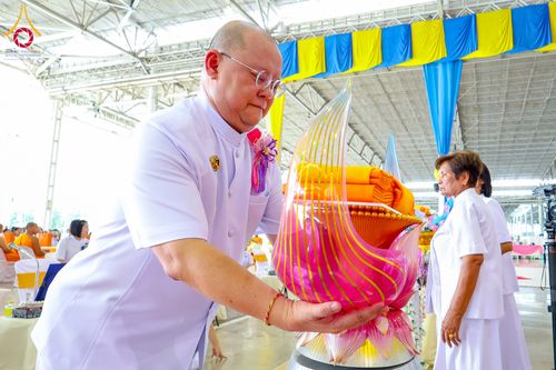 ชายสวมชุดขาวประคองพานพุ่มผ้าไตรจีวรในพิธีทอดผ้าป่า