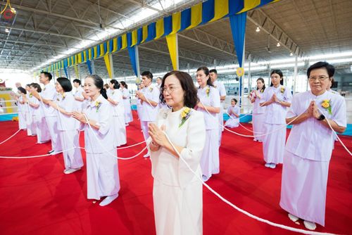 กลุ่มคนสวมชุดขาวพนมมือถือสายสิญจน์ในพิธีกรรมทางศาสนา
