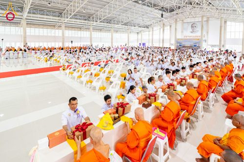 พระภิกษุสงฆ์และพุทธศาสนิกชนจำนวนมากกำลังร่วมพิธีทอดผ้าป่าภายในอาคารโถงกว้าง