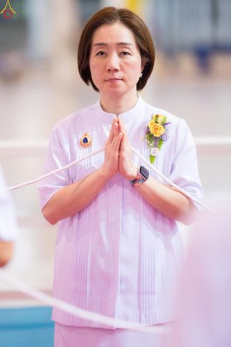 หญิงสาวสวมชุดสีขาวพนมมือถือสายสิญจน์ในพิธีการ