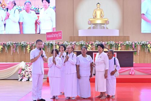 กลุ่มคนสวมชุดขาวบนเวทีงานสัมมนา มีผู้ถือป้ายหนองบัวลำภู 52 และมีพระพุทธรูปเป็นฉากหลัง