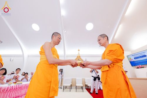 พระภิกษุสงฆ์สองรูปกำลังถือผอบทองคำบรรจุพระบรมสารีริกธาตุในพิธีทางศาสนา