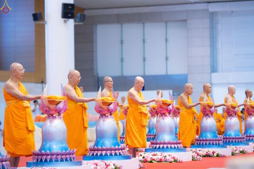 พระสงฆ์หลายรูปกำลังประกอบพิธีวางผ้าไตรบนพานพุ่มดอกบัวในพิธีทางศาสนา