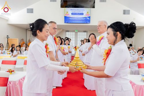 กลุ่มคนในชุดสีขาวกำลังร่วมพิธีอัญเชิญพระบรมสารีริกธาตุภายในวัด