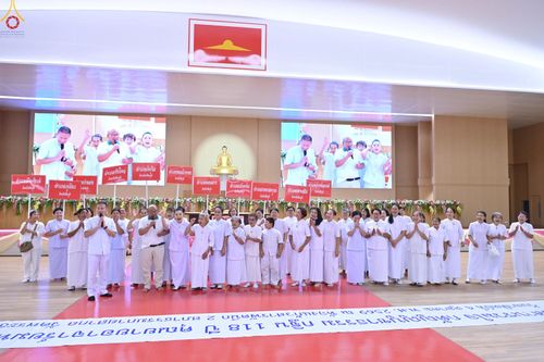 กลุ่มคนสวมชุดสีขาวถือป้ายชื่อจังหวัดยืนบนเวทีในห้องประชุมขนาดใหญ่