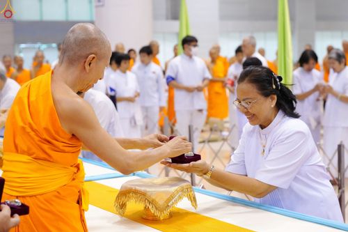 พระภิกษุกำลังส่งมอบกล่องพระของขวัญให้แก่หญิงชุดขาวในพิธีทางศาสนา