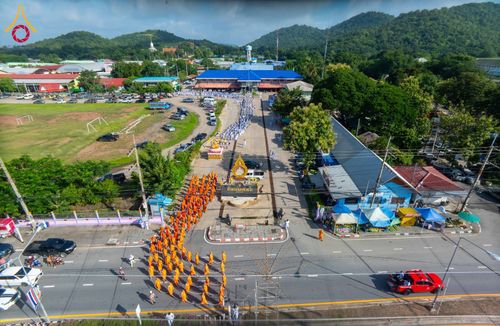 ขบวนพระภิกษุสงฆ์เดินเรียงแถวบนถนนมุ่งหน้าเข้าสู่ธุดงคสถานในมุมมองจากที่สูง