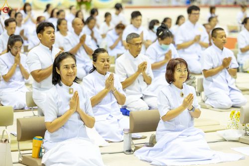 กลุ่มคนสวมชุดสีขาวนั่งพนมมือปฏิบัติธรรมภายในห้องโถง