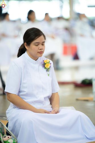 หญิงสาวสวมชุดสีขาวนั่งหลับตาทำสมาธิอย่างสงบในพิธีทางศาสนา