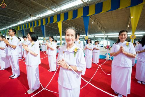 กลุ่มคนสวมชุดขาวถือสายสิญจน์ร่วมพิธีทางศาสนาภายในอาคาร