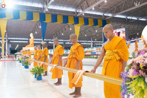 พระภิกษุสงฆ์หลายรูปยืนเรียงแถวในอาคารโถงกว้างเพื่อประกอบพิธีทางศาสนา