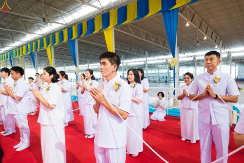 กลุ่มคนสวมชุดขาวพนมมือถือสายสิญจน์ร่วมพิธีกรรมทางศาสนาภายในอาคาร