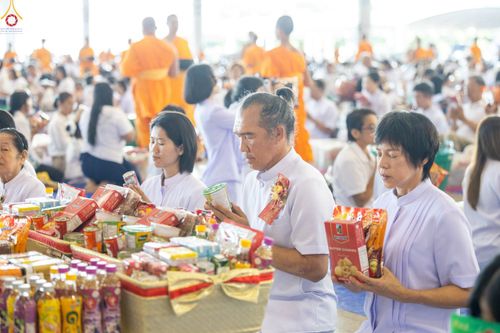 พุทธศาสนิกชนสวมชุดสีขาวถือสิ่งของเตรียมตักบาตรภายในสภาธรรมกายสากล