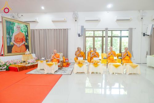 พระภิกษุสงฆ์นั่งเรียงแถวบนอาสนะในห้องประชุมเพื่อประกอบพิธีทางศาสนา