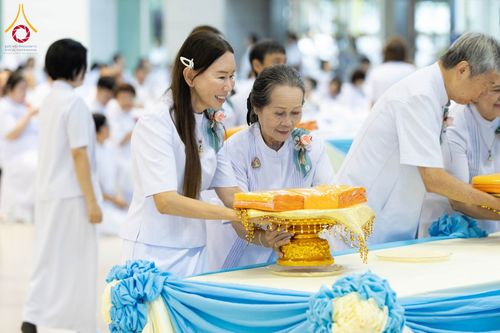 พุทธศาสนิกชนในชุดขาวกำลังถือพานผ้าไตรจีวรในพิธีทอดผ้าป่า
