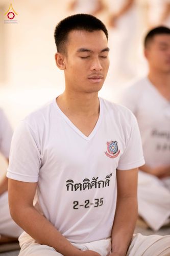 นักเรียนนายสิบตำรวจชายสวมเสื้อยืดสีขาวนั่งหลับตาทำสมาธิ