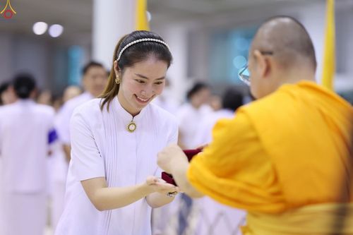 หญิงสาวชุดขาวกำลังรับมอบพระของขวัญจากพระภิกษุสงฆ์