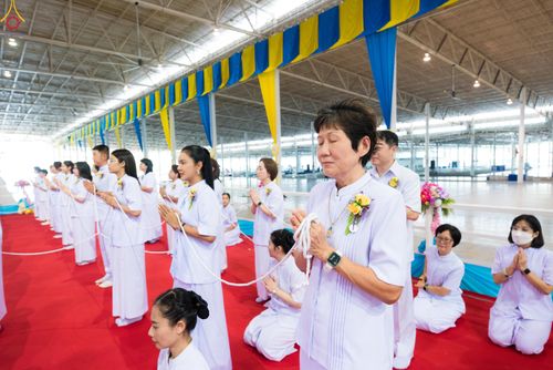 กลุ่มคนสวมชุดขาวถือสายสิญจน์ร่วมพิธีทางศาสนาภายในอาคาร