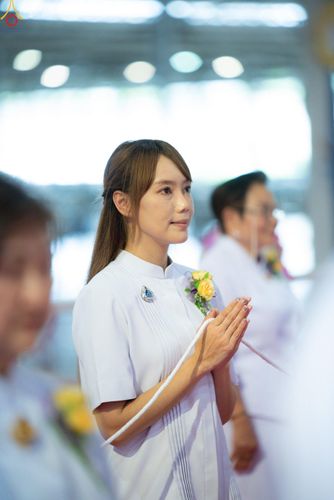 หญิงสาวสวมชุดขาวพนมมือถือสายสิญจน์ในพิธีกรรมทางศาสนา