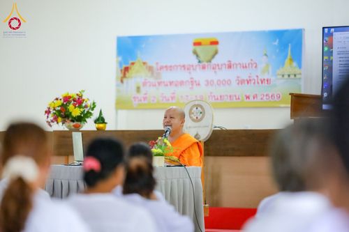 พระภิกษุสงฆ์นั่งบรรยายธรรมต่อหน้าผู้เข้าร่วมโครงการในชุดสีขาวภายในห้องประชุม