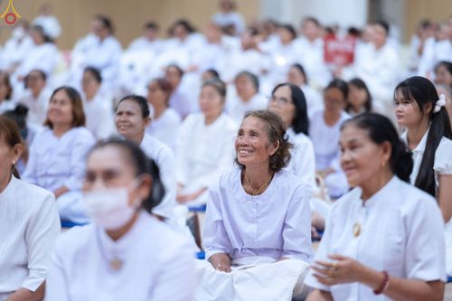 กลุ่มพุทธศาสนิกชนสวมชุดสีขาวนั่งฟังการบรรยายธรรมภายในอาคาร