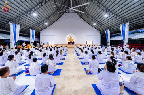 ผู้เข้าร่วมโครงการอบรมสวมชุดสีขาวนั่งปฏิบัติธรรมภายในอาคารโถงกว้าง