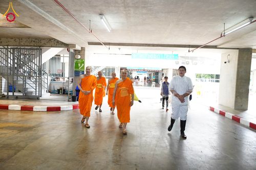 พระภิกษุสงฆ์และฆราวาสกำลังเดินสำรวจภายในอาคารจอดรถคอนกรีต