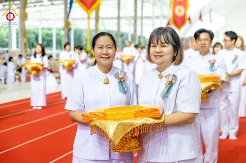 หญิงสองคนสวมชุดสีขาวถือพานผ้าไตรจีวรสีเหลืองทองในพิธีทางศาสนา