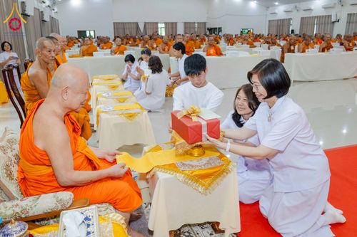 กลุ่มคนชุดขาวกำลังถวายของขวัญแด่พระภิกษุสงฆ์ในงานสัมมนา