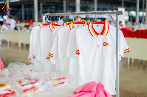 เสื้อโปโลสีขาวคอปกสีแดงเหลืองแขวนบนราวเหล็กภายในอาคาร