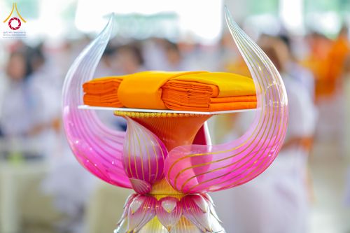 ผ้าไตรจีวรวางอยู่บนพานรูปดอกบัวสีชมพูทองในพิธีทางศาสนา