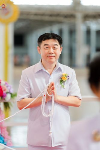ชายสวมชุดขาวพนมมือถือสายสิญจน์ในพิธีทางศาสนา