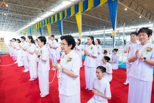 กลุ่มคนสวมชุดขาวถือสายสิญจน์ประกอบพิธีกรรมทางศาสนาภายในอาคาร