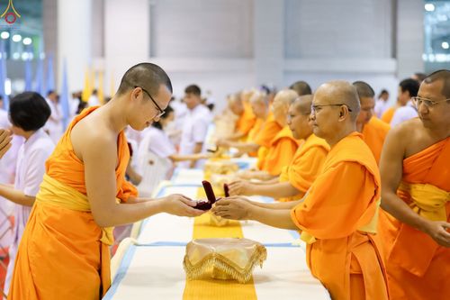 พระภิกษุสงฆ์ในจีวรสีส้มกำลังส่งมอบกล่องพระของขวัญให้แก่กันในพิธีทางศาสนา