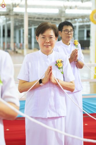 หญิงวัยกลางคนสวมชุดสีขาวพนมมือไหว้ในพิธีทางศาสนา