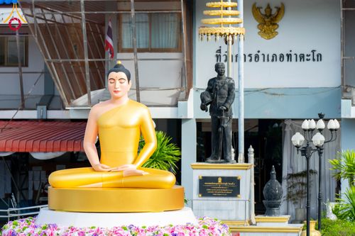 พระพุทธรูปสีทองประดิษฐานอยู่หน้าอนุสาวรีย์และอาคารที่ทำการอำเภอ