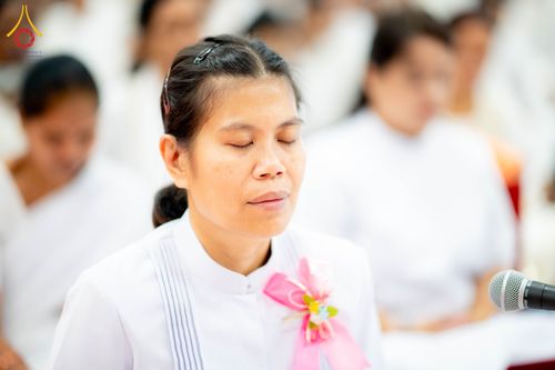 หญิงไทยสวมชุดขาวหลับตาทำสมาธิในพิธีกรรมทางศาสนา