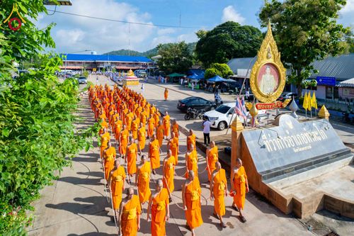 ขบวนพระภิกษุสงฆ์จำนวนมากเดินเรียงแถวในจีวรสีส้มบนถนนกลางแจ้ง