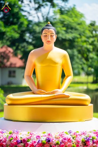 พระพุทธรูปปางสมาธิสีทองประทับนั่งบนฐานวงกลม มีดอกไม้ประดับตกแต่งอยู่ด้านหน้า