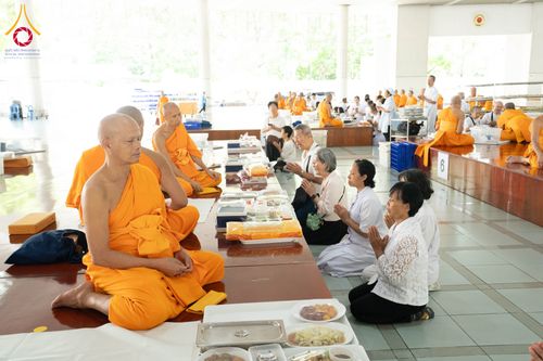 พระภิกษุสงฆ์และสาธุชนนั่งพนมมือเตรียมถวายภัตตาหารภายในหอฉันคุณยายอาจารย์ฯ วัดพระธรรมกาย