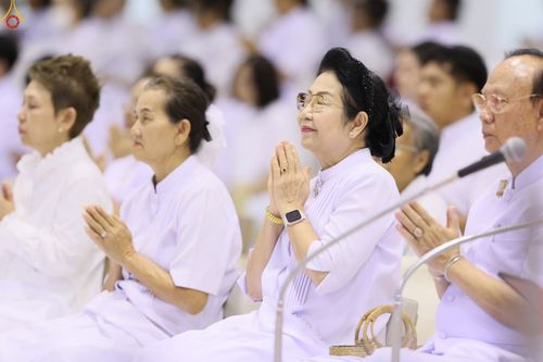 กลุ่มคนสวมชุดสีขาวนั่งพนมมือด้วยความสงบในพิธีกรรมทางศาสนา