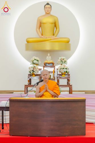 พระภิกษุสงฆ์กำลังประนมมือบรรยายธรรมหน้าพระพุทธรูปสีทอง