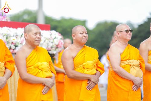 พระภิกษุสงฆ์สามรูปยืนเรียงแถวในชุดจีวรสีเหลืองทองด้วยท่าทางสงบในงานพิธี