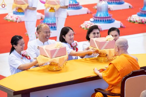 กลุ่มคนในชุดสีขาวกำลังถวายพานผ้าป่าแด่พระภิกษุสงฆ์ในพิธีทางศาสนา